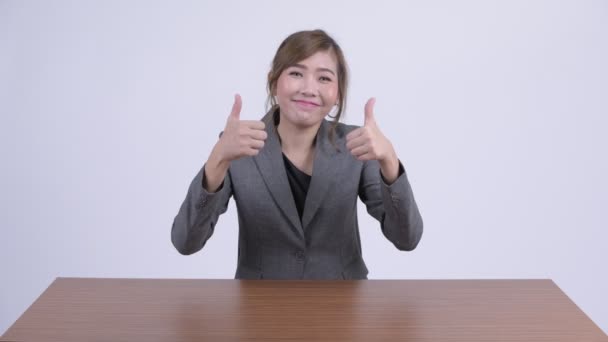 Joven feliz asiática mujer de negocios buscando emocionado mientras dando pulgares hacia arriba en el escritorio — Vídeos de Stock