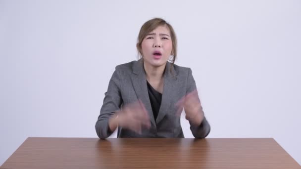 Молодая сердитая азиатская деловая женщина говорит и жалуется за столом — стоковое видео
