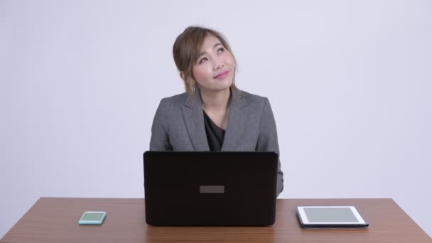 年轻快乐的亚洲女商人一边思考, 一边在工作中使用笔记本电脑 — 图库视频影像