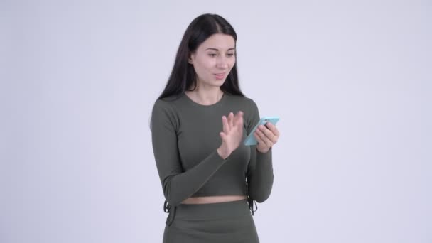 Щаслива молода красива жінка використовує телефон і виглядає здивованою — стокове відео