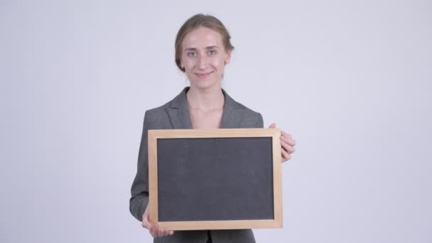 Happy young blonde businesswoman thinking while holding blackboard — Stock Video