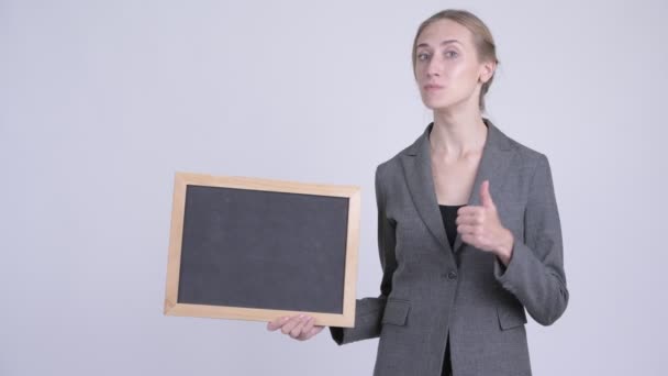 Jovem mulher de negócios loira feliz segurando quadro negro e dando polegares para cima — Vídeo de Stock
