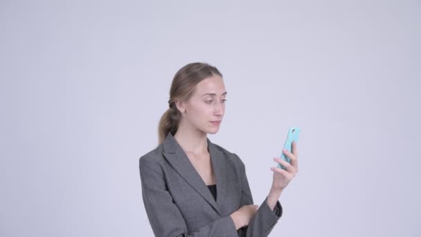 Jovem mulher de negócios loira feliz usando telefone e olhando surpreso — Vídeo de Stock