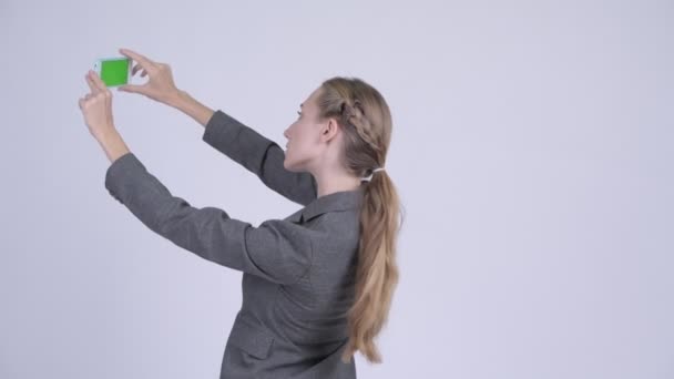 Вид спереду молодої блондинки бізнес-леді фотографується з телефоном — стокове відео