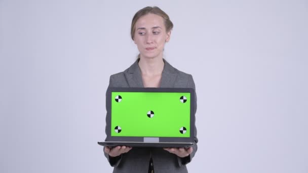 Happy young blonde businesswoman thinking while showing laptop — Stock Video