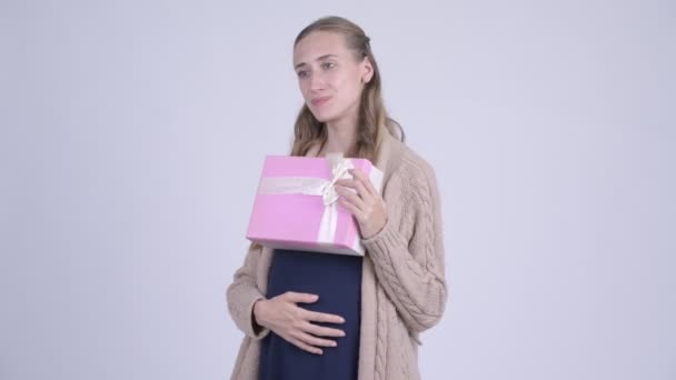 Счастливая беременная женщина думает, держа в руках подарочную коробку — стоковое видео