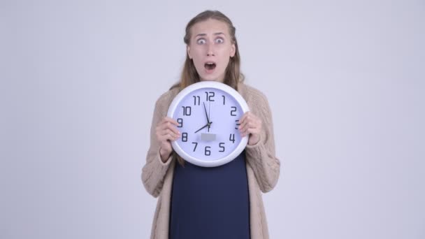 Ung stressad gravid kvinna håller väggklocka och ser chockad — Stockvideo