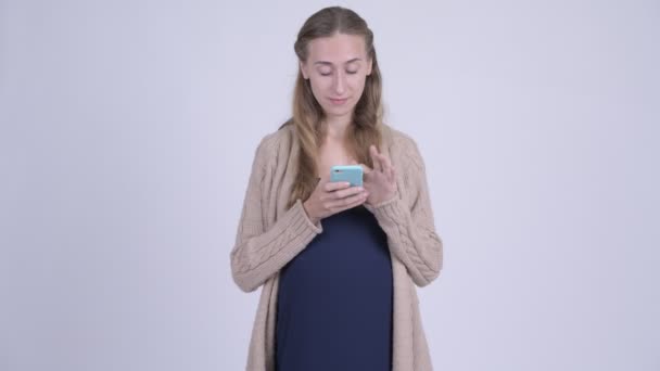 Glad ung gravid kvinna använda telefon och få goda nyheter — Stockvideo