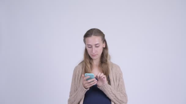 Счастливая молодая беременная женщина с телефоном и выглядит удивленной — стоковое видео