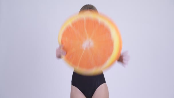 Feliz joven rubia en traje de baño lanzando almohada naranja como concepto saludable — Vídeo de stock