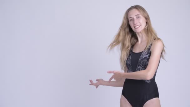 Joyeux jeune femme blonde en maillot de bain montrant quelque chose à l'arrière — Video