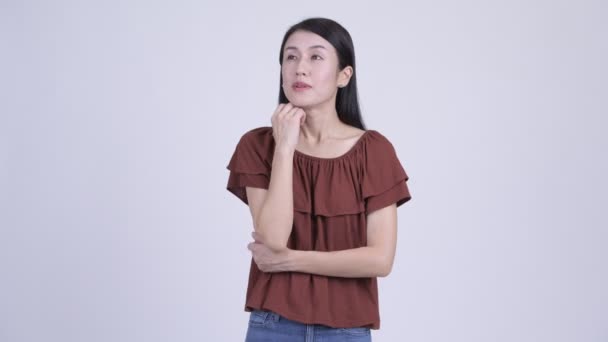 Feliz bela mulher asiática pensando e olhando para cima — Vídeo de Stock