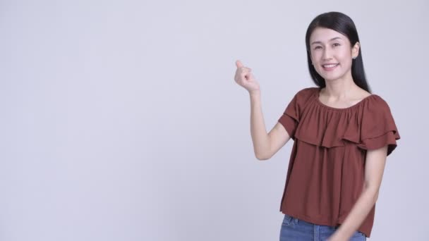 Glad vacker asiatisk kvinna knäppa fingrarna och visar något — Stockvideo