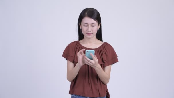 快乐美丽的亚洲妇女使用电话和得到好消息 — 图库视频影像