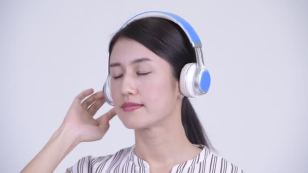 Лицо счастливой красивой азиатской предпринимательницы, слушающей музыку с закрытыми глазами — стоковое видео