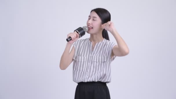 Счастливая азиатская бизнесвумен поет с микрофоном — стоковое видео