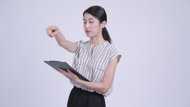 Hermosa mujer de negocios asiática dirigiendo mientras lee en el portapapeles — Vídeos de Stock