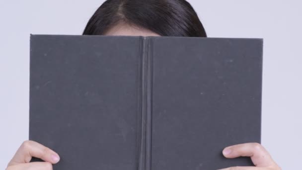 Twarz Asian kobieta myślenia podczas krycia twarz z książki — Wideo stockowe