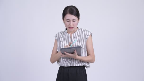 Drukke Aziatische zakenvrouw praten aan de telefoon en het gebruik van digitale tablet — Stockvideo