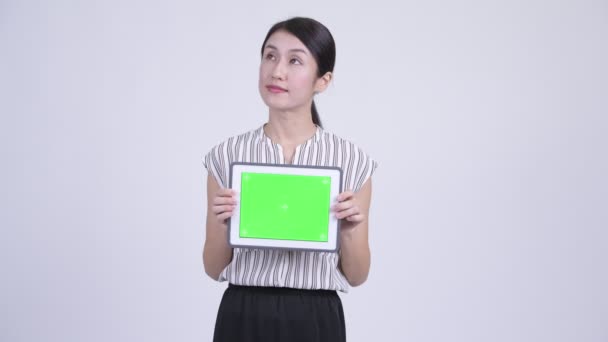 Glada vackra asiatiska affärskvinna tänkande samtidigt visar digitala tablett — Stockvideo