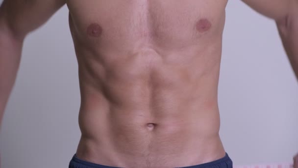 Мускулистый мужчина с мерной лентой вокруг пояса без рубашки — стоковое видео