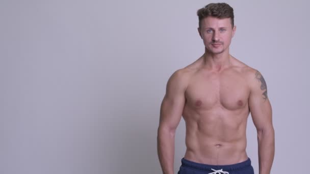 Happy muscular bearded man showing something shirtless — Stock Video