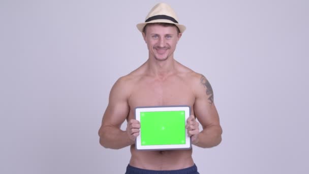 Счастливый мускулистый бородатый турист показывает цифровой планшет без рубашки — стоковое видео