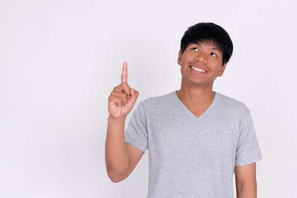 Портрет счастливого молодого азиата, думающего и указывающего вверх — стоковое фото