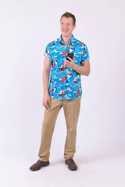 Full body shot of young happy tourist man thinking while using phone — Stock Photo, Image