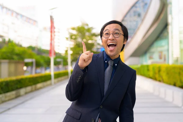 Szczęśliwy azjatycki biznes biznesmen myślenia przy palcem wskazującym w górę na zewnątrz — Zdjęcie stockowe