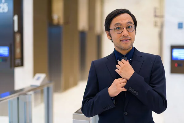 Asiatique homme d'affaires ajuster cravate à l'intérieur de l'immeuble de bureaux — Photo