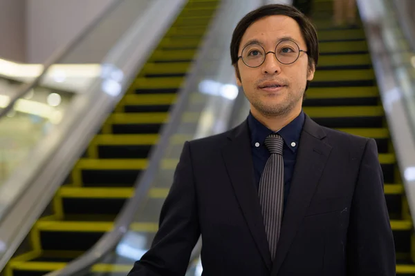 Asiatique homme d'affaires à l'escalator à l'intérieur de l'immeuble de bureaux — Photo