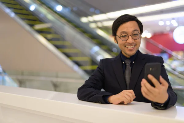 Happy Asian businessman using phone inside the office building — Stock Photo, Image