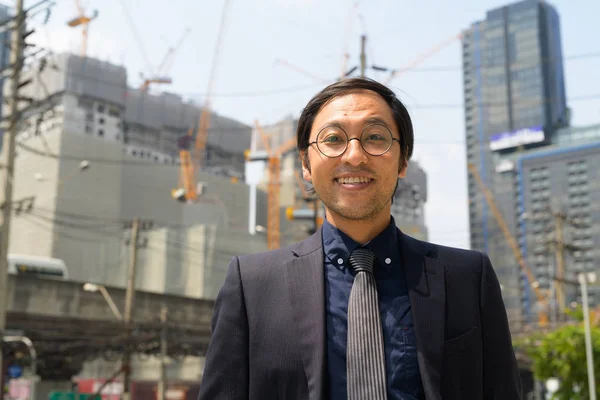 Visage de heureux homme d'affaires asiatique souriant contre la vue du site de construction — Photo