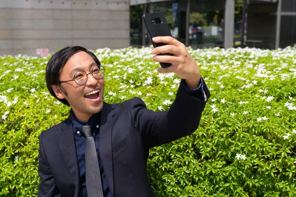 Feliz asiático hombre de negocios tomando selfie con la naturaleza en la ciudad —  Fotos de Stock