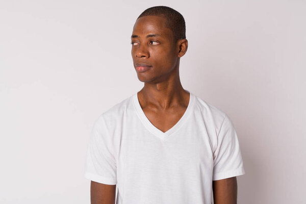 Studio shot of young handsome bald African man against white background