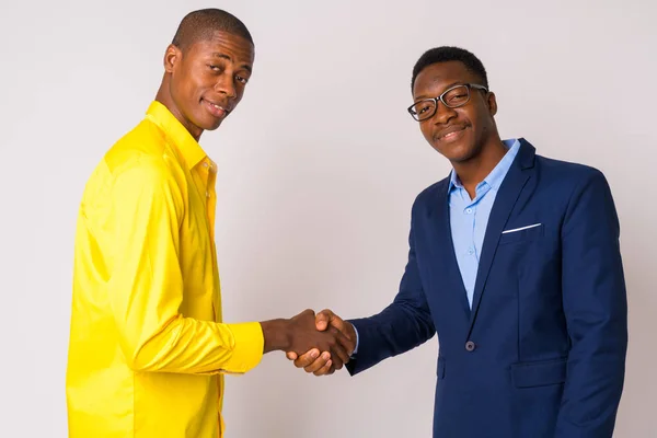 Two young happy African businessmen shaking hands together