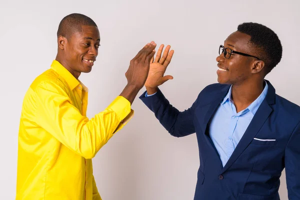 Two young happy African businessmen giving high five together