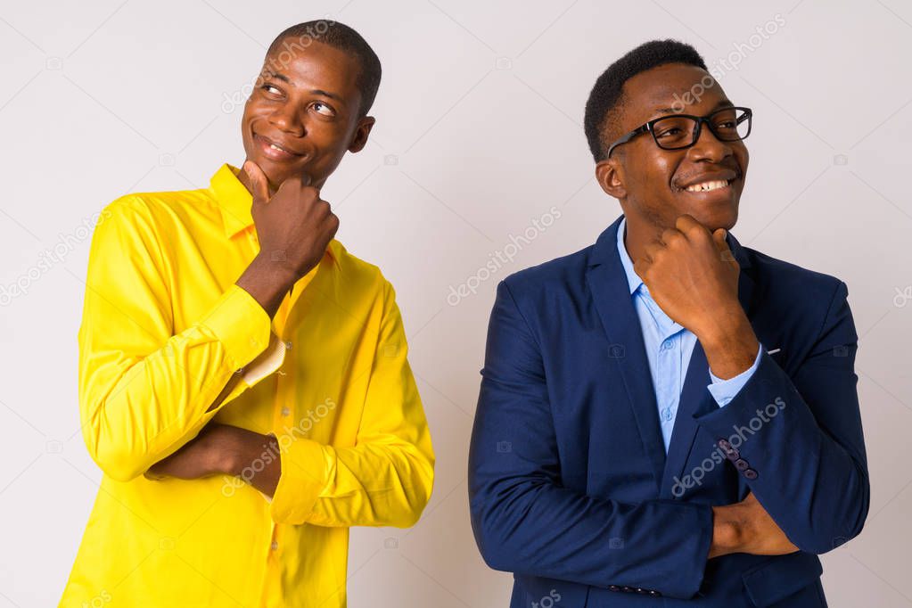 Two young happy African businessmen thinking together