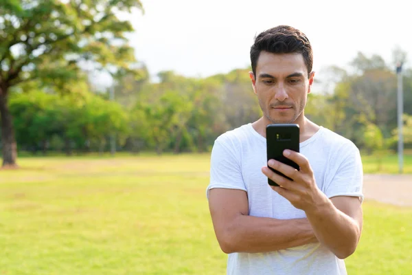 Jeune homme hispanique beau utilisant le téléphone au parc — Photo