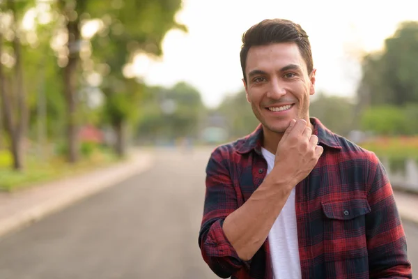 Parkta gülümseyen mutlu yakışıklı İspanyol hipster delikanlı