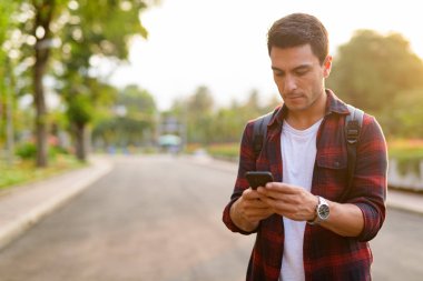Telefonunuzun ve parkta genç yakışıklı İspanyol hipster adam
