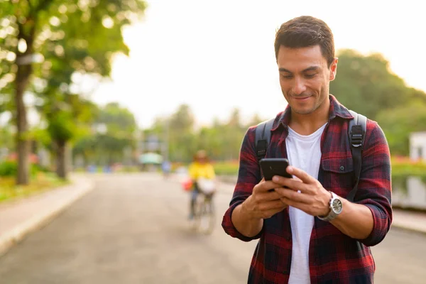 Telefonunuzun ve parkta mutlu yakışıklı İspanyol hipster delikanlı