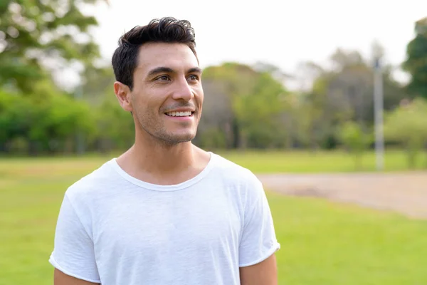 Gesicht eines glücklichen jungen, gut aussehenden hispanischen Mannes, der im Park denkt — Stockfoto