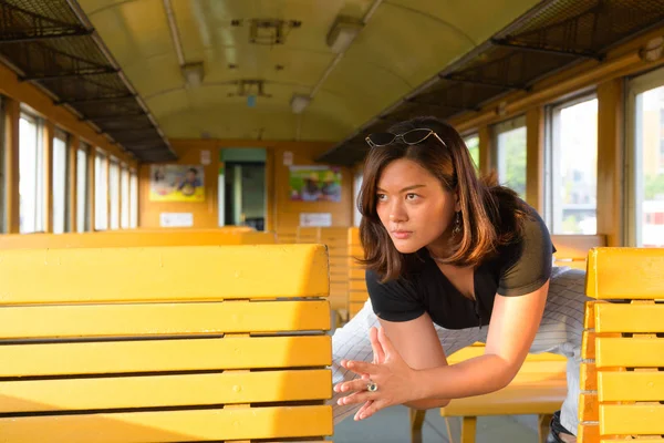 Mladé krásné asijské turistické žena při pohledu přes okno uvnitř vlaku — Stock fotografie