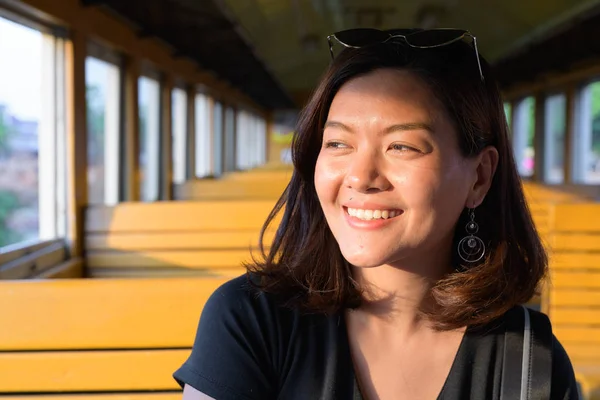 Tvář ženy šťastné mladé krásné asijské turistické usmívající se uvnitř vlaku — Stock fotografie