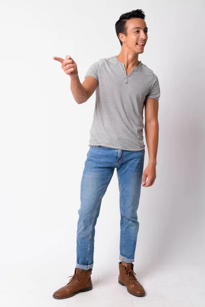 Full body shot of happy Hispanic man pointing finger and looking away — Stock Photo, Image