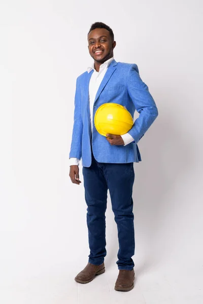 Full body shot de feliz joven empresario africano sonriendo con hardhat —  Fotos de Stock