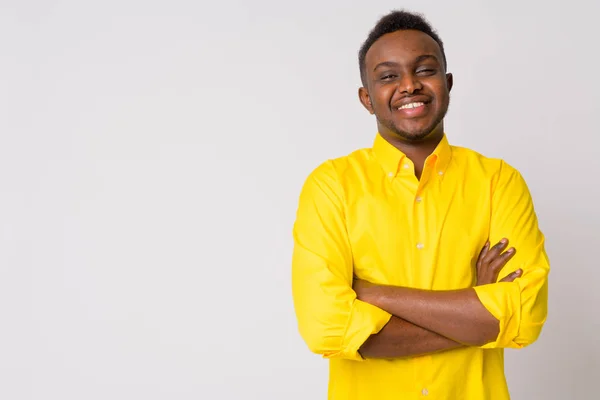 Glücklicher junger afrikanischer Geschäftsmann mit gelbem Hemd, lächelnd und verschränkten Armen — Stockfoto