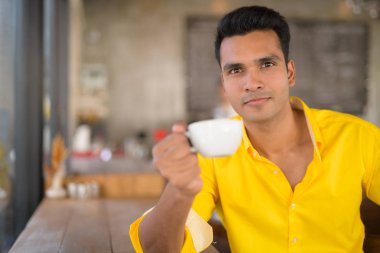 Genç yakışıklı Hintli adam pencerenin coffee shop kahve içme